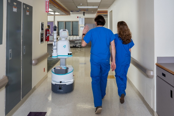 Moxi가 병원 물품을 운반하며 직원들과 인사를 나누고 있다 (출처: Diligent Robotics 공식 홈페이지)